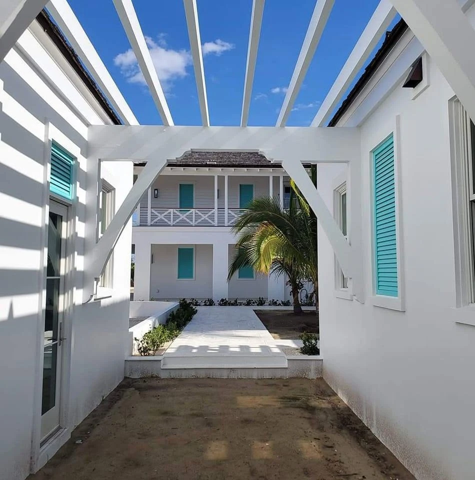 Turquoise shutters and white pergola beneath a Bahamian blue sky