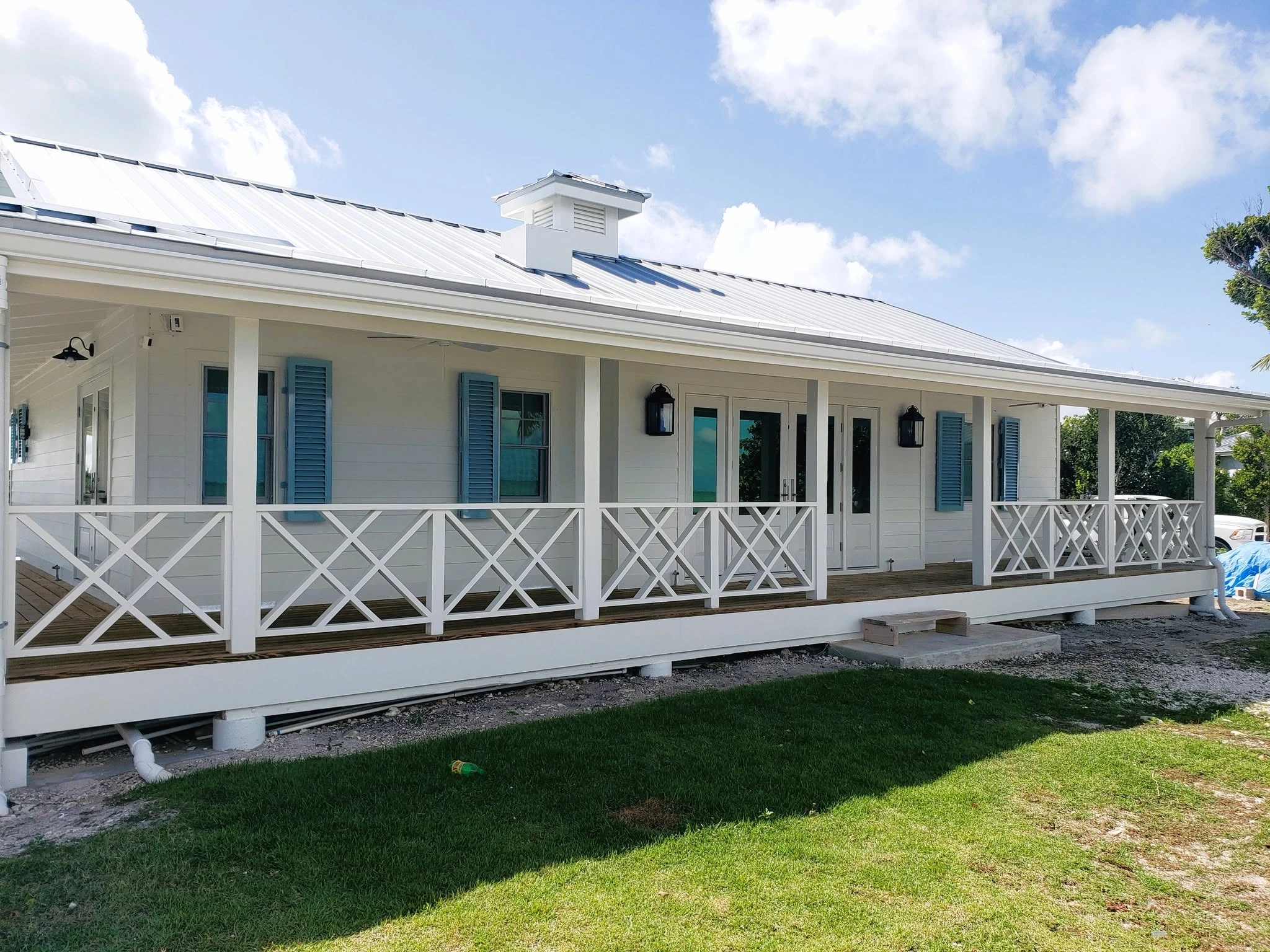 White Bahamian home with blue shutters and a sunny veranda
